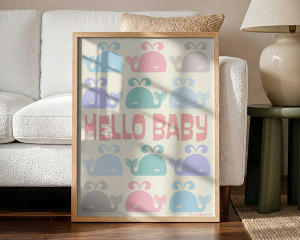 Framed Hello Baby Whales ocean nursery print displayed above a cot.